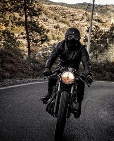 a man riding on the back of a motorcycle down a curvy road