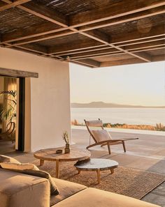 a living room with couches and tables on the floor next to an ocean view