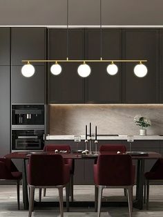 a dining room table with chairs and lights hanging from it's ceiling over the kitchen