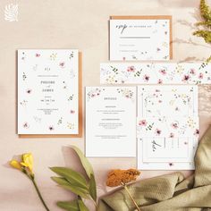 the wedding stationery is laid out with flowers and greenery