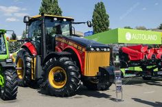 two tractors parked next to each other in a parking lot with people looking at them