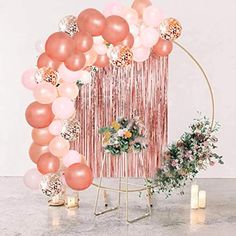 the balloon arch is decorated with pink, peach and white balloons