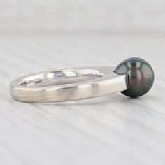 Gem: Cultured Pearl - 7.5 mm, Round Shape, Gray / Black Color - Natural Diamond - 0.02 Total Carats, Round Brilliant Cut, G Color, SI1 Clarity Metal: 18k White Gold Weight: 6.4 Grams Stamps: 750, Movado maker's mark Face Height: 7.6 mm Rise Above Finger: 9.6 mm This ring is a size 5 3/4. Please contact us for sizing options. Each piece is thoroughly examined and refinished as needed by our professional jewelers, graded by our in-house GIA (Gemological Institute of America) Graduate Gemologist, a Classic Tahitian Pearl Rings As Gift, Formal Minimalist Pearl Ring With Polished Finish, Minimalist Polished Pearl Ring For Formal Occasions, Tahitian Pearl Jewelry With Brilliant Cut, Formal Polished Pearl Ring With Round Cut, Formal Stackable Pearl Ring Fine Jewelry, Formal Stackable Pearl Ring, Fine Jewelry, Formal Round Cut Polished Pearl Ring, Stackable Pearl Ring For Formal Occasions