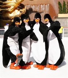 three penguins standing next to each other in front of a fountain with gold statues behind them