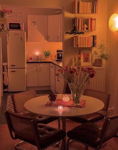 a small kitchen with a table and chairs in the center, next to a refrigerator