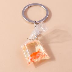 an orange fish in a clear plastic bag on a keychain with a metal ring