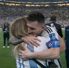 two people hugging each other on a soccer field