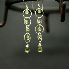 "Peridot Silver Earrings Peridot drops Briolettes and beads are wrapped with high quality sterling silver and wire and enclosed within a rings of a large link silver chain. Light weight elegant and simple. Perfect for special occasion or casual everyday wear. Mesurements: Peridot Briolette : 10mm The earrings drop around 2\" from the bottom of the hook. Ready to Ship. All items are shipped in a jewelry gift box with Shoshka Boutique logo. *Please Note that my jewelry contain an actual gemstones Peridot Dangle Earrings With Ear Wire, Silver Dangle Peridot Earrings, Silver Peridot Dangle Earrings, Light Green Earrings, Funky Jewellery, Flower Earrings Gold, Unique Handcrafted Jewelry, Green Gem, Peridot Earrings