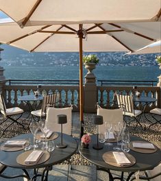 an outdoor dining area with tables and umbrellas overlooking the ocean in nice weather conditions