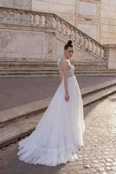 a woman in a white dress is standing on the street