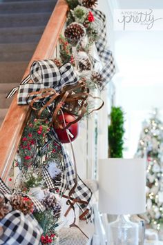 a christmas garland with pine cones, berries and plaid ribbon on the bannister