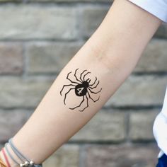 a woman's arm with a black spider tattoo on the left side of her arm