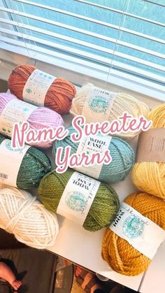 several balls of yarn sitting on top of a table next to a sign that says name sweater yarns