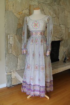 A stunning and rare dress with a mandala print A beautiful 60s maxi dress with a cotton lining and sheer overlay The fabric is a gauze type sheer The dress has an empire line and scoop open back Long sleeves with cuffs, these are not lined but are see through The colors are pink, green, and a dark blue Fits like a small to x small Label: House of Arts Made in India The mandala has great significance in buddhism signifying creation and the cosmos in a circle art form Measurements: 18 inches armpi Bohemian Fitted Full-length Maxi Dress, Fitted Bohemian Full Length Maxi Dress, Bohemian Maxi Dress With Empire Waist For Garden Party, Fitted Vintage Maxi Dress With Boho Print, Bohemian Empire Waist Maxi Dress, Vintage Flowy Maxi Dress For Festivals, Bohemian Empire Waist Fitted Maxi Dress, Vintage Fitted Maxi Dress For Festival, Bohemian Fitted Maxi Dress With Empire Waist