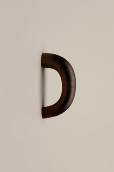 a close up of a metal object on a white wall with a black hook in the middle