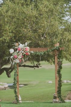 an outdoor wedding ceremony setup with flowers and greenery on the altar, in front of a golf course