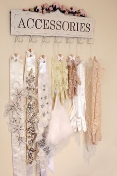 there is a sign that says accessories hanging on the wall next to some dresses and gloves