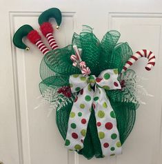 a green mesh wreath with candy canes and christmas decorations hanging on the front door