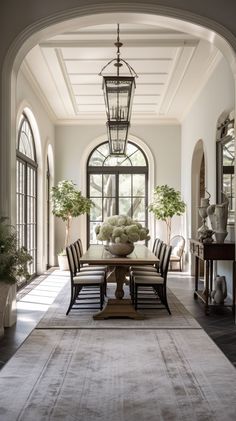 a dining room table with chairs and vases on top of it in front of an arched doorway