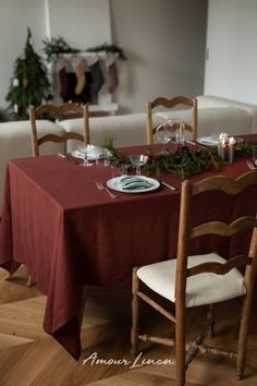 the table is set for christmas dinner with red linens and greenery on it