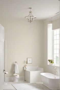 an all white bathroom with chandelier and bathtub