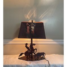 a lamp that is sitting on top of a bed with a horse and rider underneath it