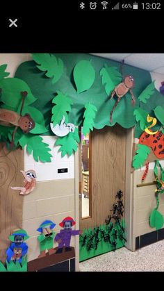 a classroom door decorated with paper cut outs and jungle animals on the front, trees in the back