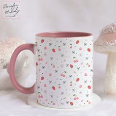 a pink and white coffee mug sitting on top of a table next to some mushrooms