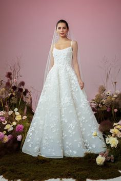 a woman standing in front of flowers wearing a wedding dress