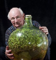 an old man holding a large vase filled with plants