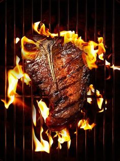 a steak is grilled on the grill with flames coming out of it's side