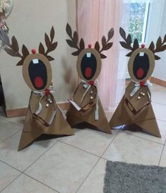 three brown paper christmas decorations sitting on top of a tile floor next to a window