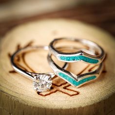 two silver rings with blue and white stones on them sitting on a piece of wood