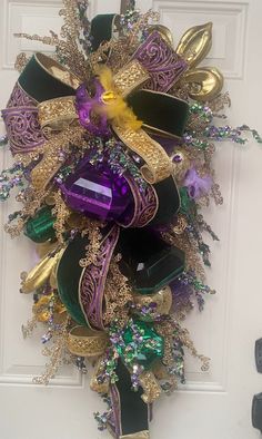 a purple, green and gold christmas wreath on the front door for someone's house