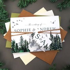 wedding stationery with pine trees and evergreens on them, including the couple's initials