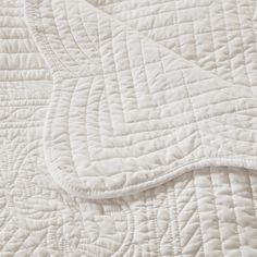 an unmade bed with white quilting on it