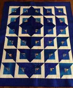 a blue and white quilted table topper on a wooden floor with an image of a star in the center