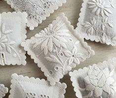 several white embroidered napkins on top of a wooden table