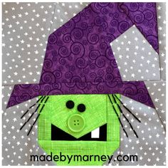 a close up of a green and purple patchwork cat with a hat on it's head