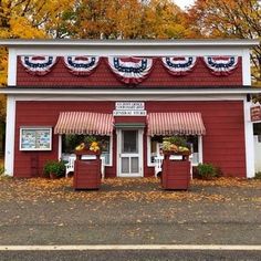 a red and white building sitting on the side of a road next to autumn trees