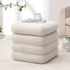 a stack of towels sitting on top of a white floor next to a chair and ottoman