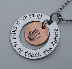 two silver and copper necklaces with hand prints on them