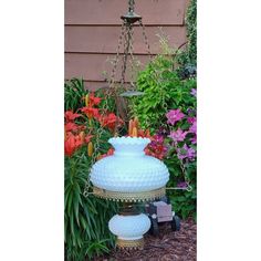 a large white vase sitting on top of a table next to flowers and other plants