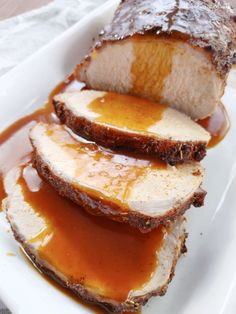 slices of meat covered in gravy on a white plate