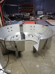 an oval metal table in the middle of a room with lots of tools on it