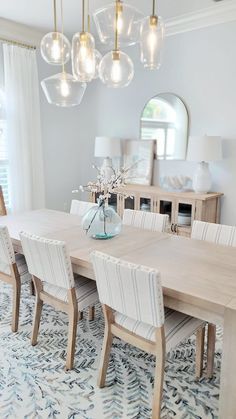 a dining room table and chairs with lights hanging from the chandelier above it