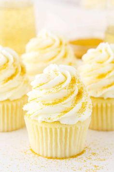 three cupcakes with white frosting and gold sprinkles on top