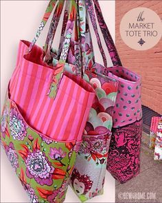 the market tote trio is made from fabric and has multiple pockets for purses