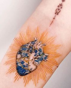 a heart tattoo on the arm with an arrow and sunburst in the middle