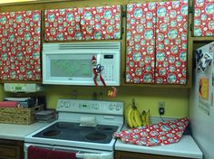 the kitchen is decorated with red and white decor, including hanging curtains over the stove